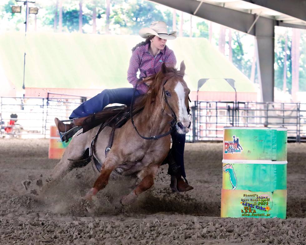 Young barrel racer making a turn under the arena lights